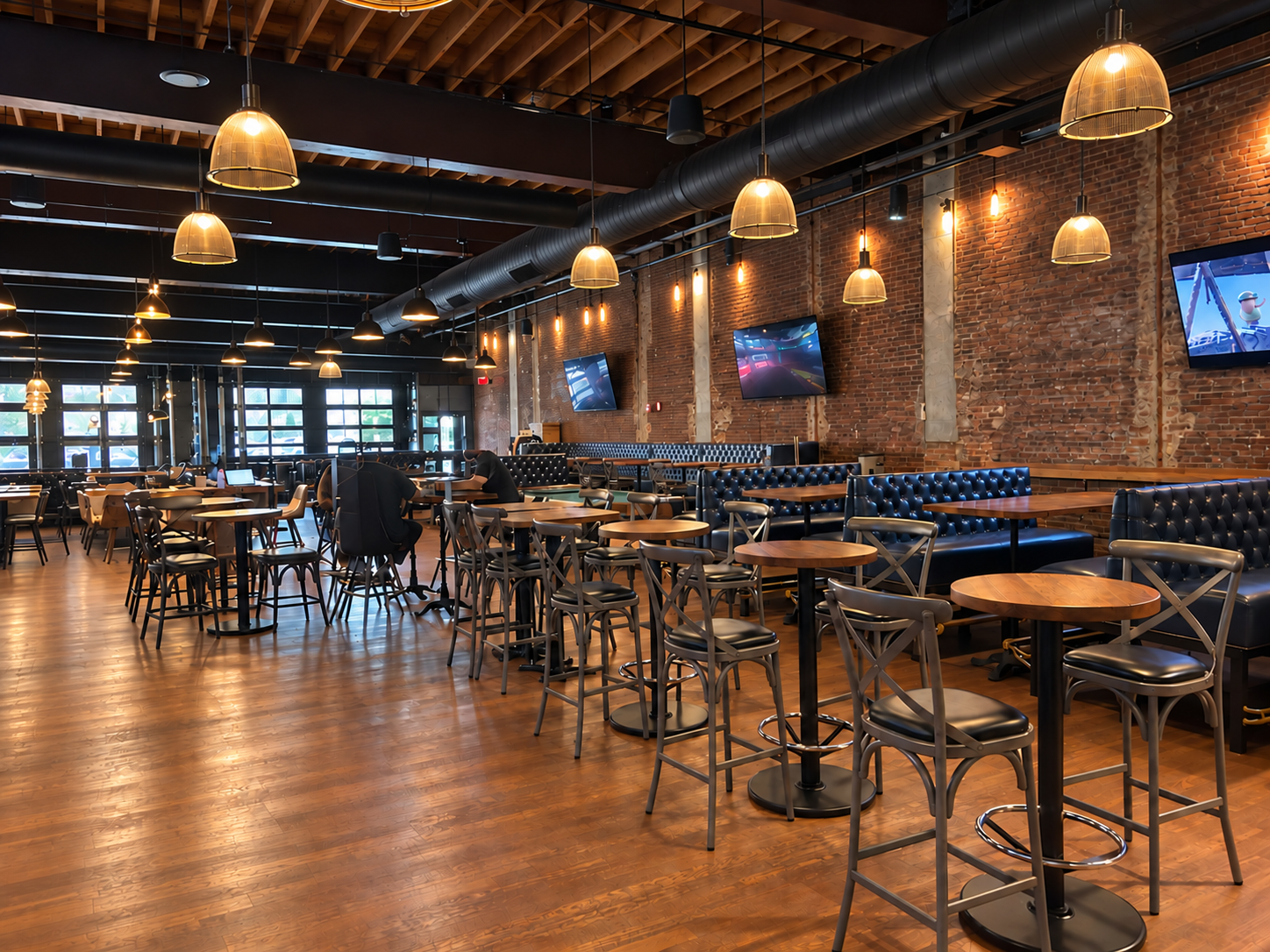 Publick House dining room with exposed brick, warm pendant lighting, wood tables, and tufted booths